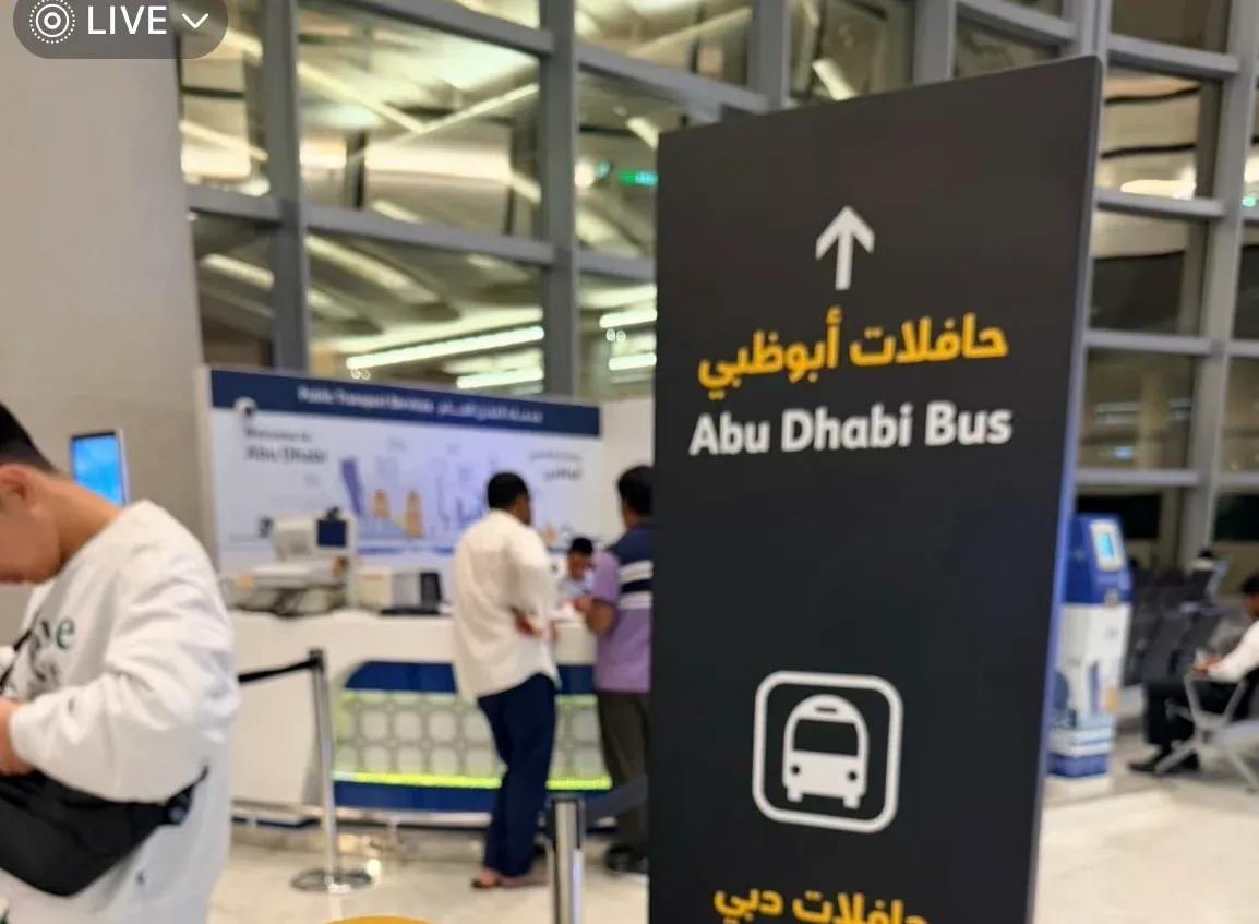 The Hafilat desk in the arrivals hall, with a black pillar pointing to Abu Dhabi buses on one side and Dubai buses on the other