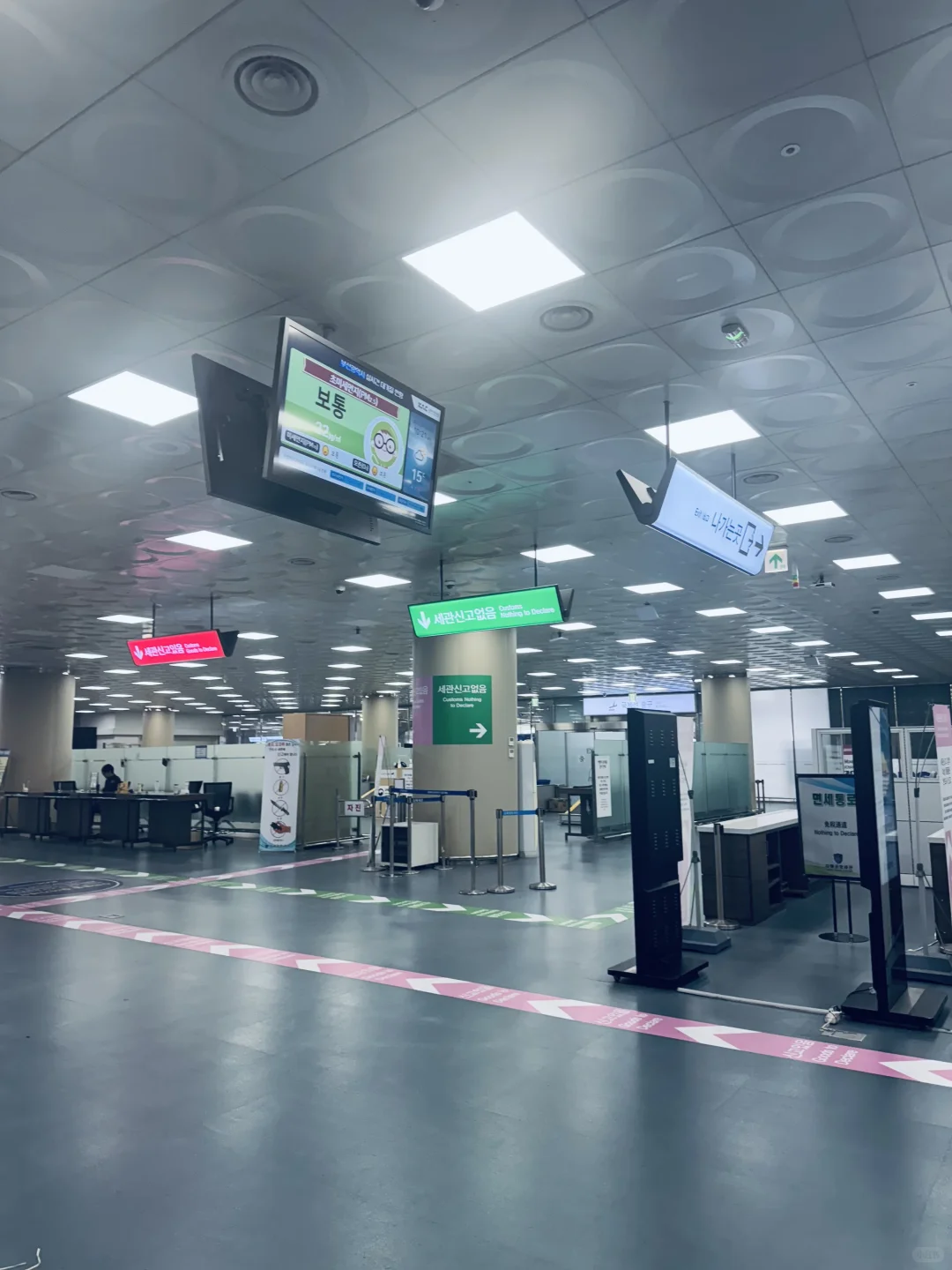 The yellow EXIT arrows on the arrivals hall floor, pointing to the doors