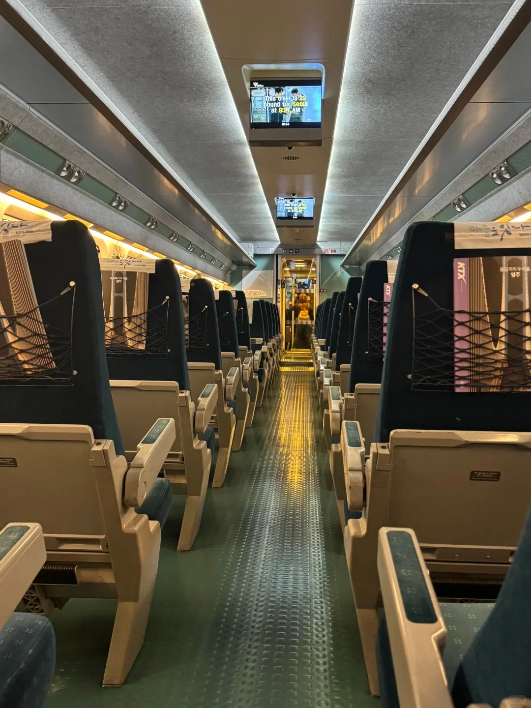 Inside a KTX carriage: reserved seats either side of the aisle, screens in the ceiling