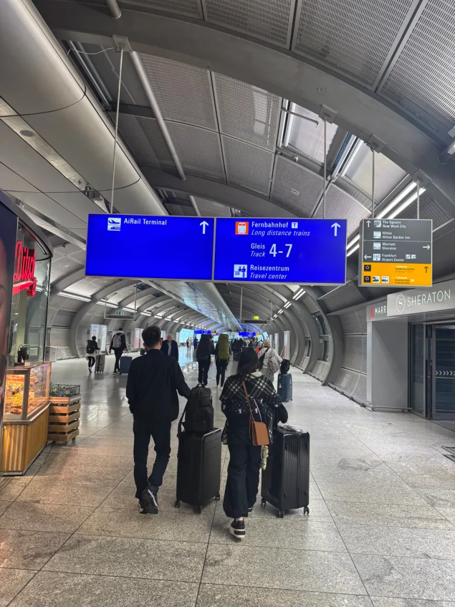 The long corridor to the Fernbahnhof: glass walls, an angled steel roof and travellers walking in single file with their luggage