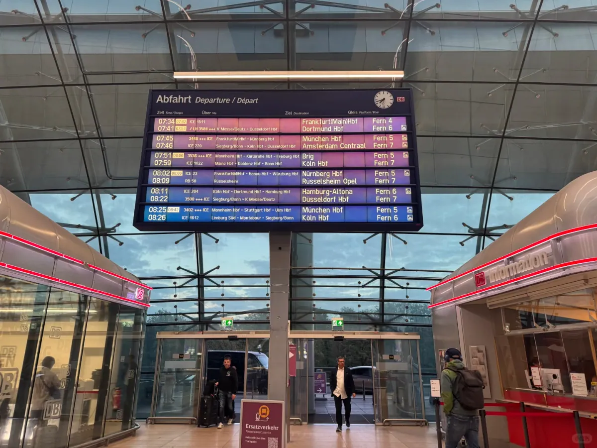The Abfahrt/Departure board in the Fernbahnhof hall, listing ICE services, destinations and Gleis 4–7 platforms, with the DB Information desk to the right