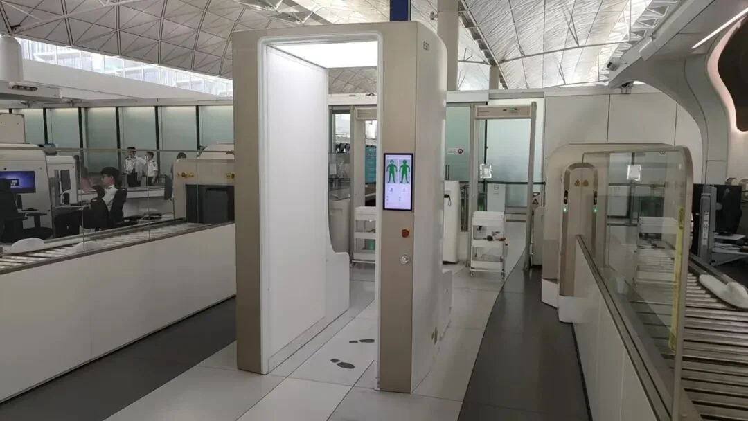 A security lane at Hong Kong International: a millimetre-wave body scanner, baggage CT machines and automatic tray return