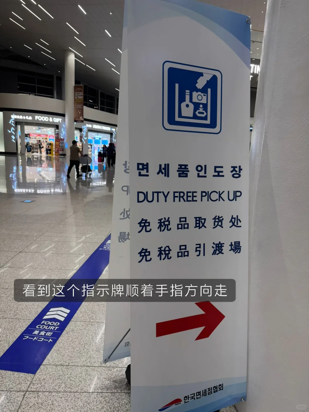 The blue "Duty Free Pick Up" sign on level 3, with an arrow towards the escalator