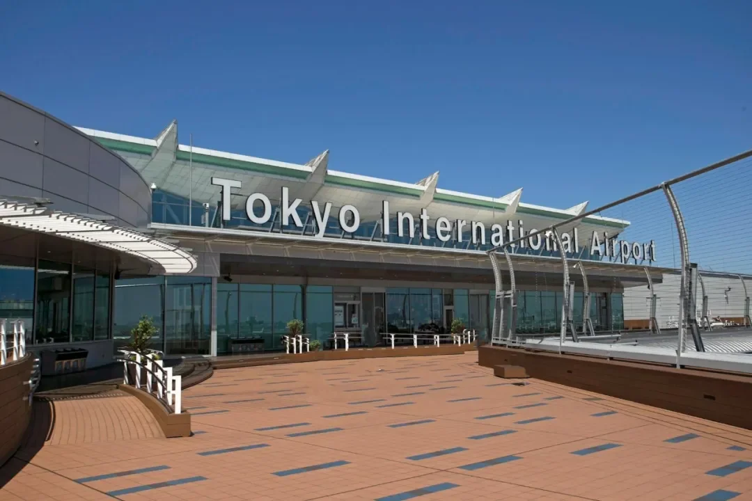 An airport terminal building, with "Tokyo International Airport" over the entrance