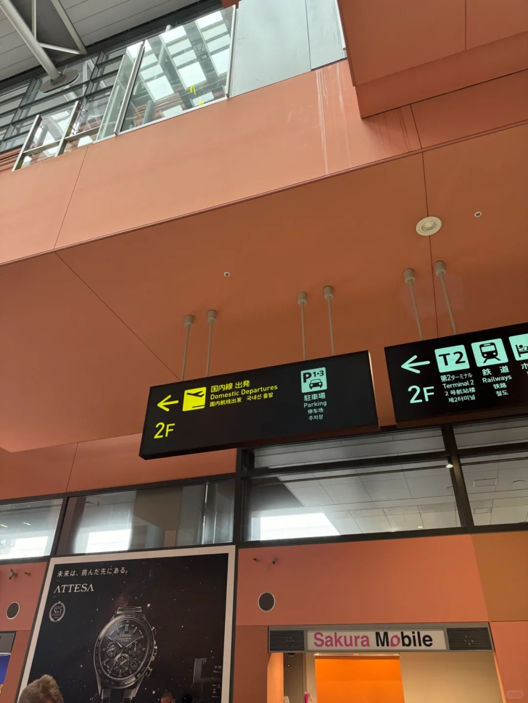 Signs on the arrivals level at Kansai Airport T1: railways, Terminal 2 and parking