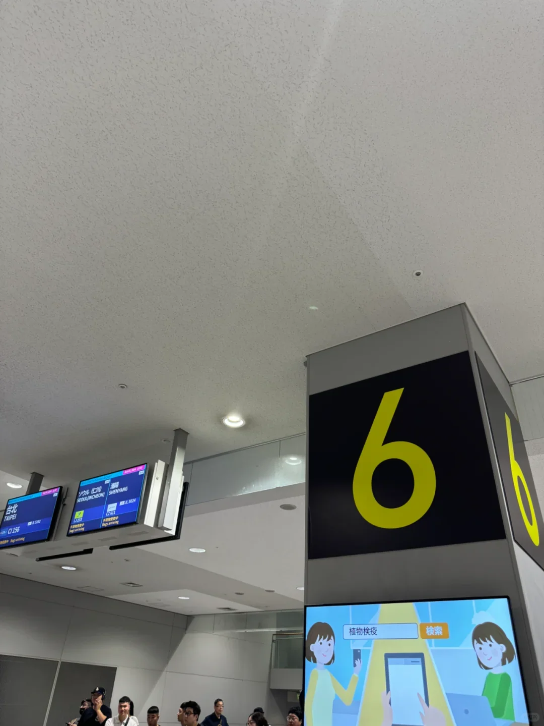 Flight information screens and a plant quarantine notice along the arrivals corridor at Kansai Airport