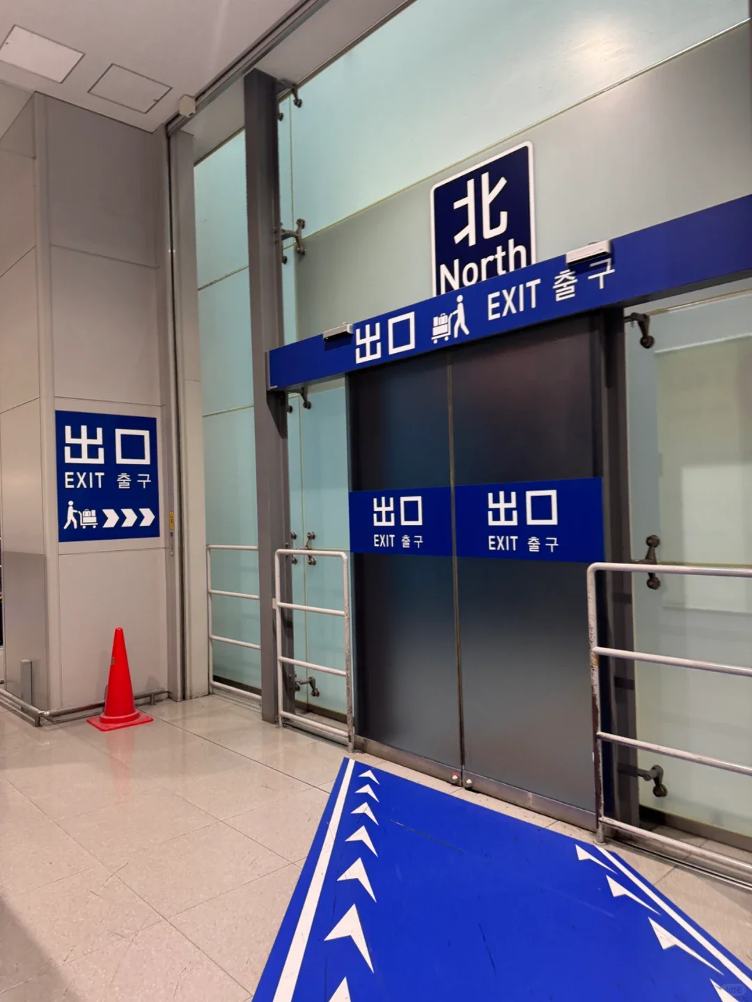 The north exit on the arrivals level, with blue arrows pointing the way out