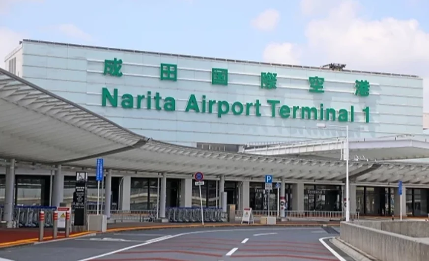 The exterior of Narita Airport Terminal 1, with the green Narita Airport Terminal 1 sign under the canopy