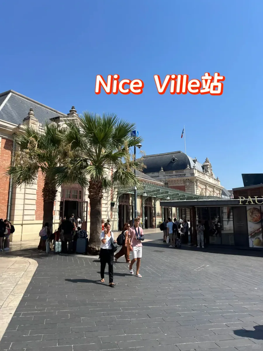 The facade of Nice-Ville station: pale stone walls, arched windows and palm trees, with a "Nice Ville" sign