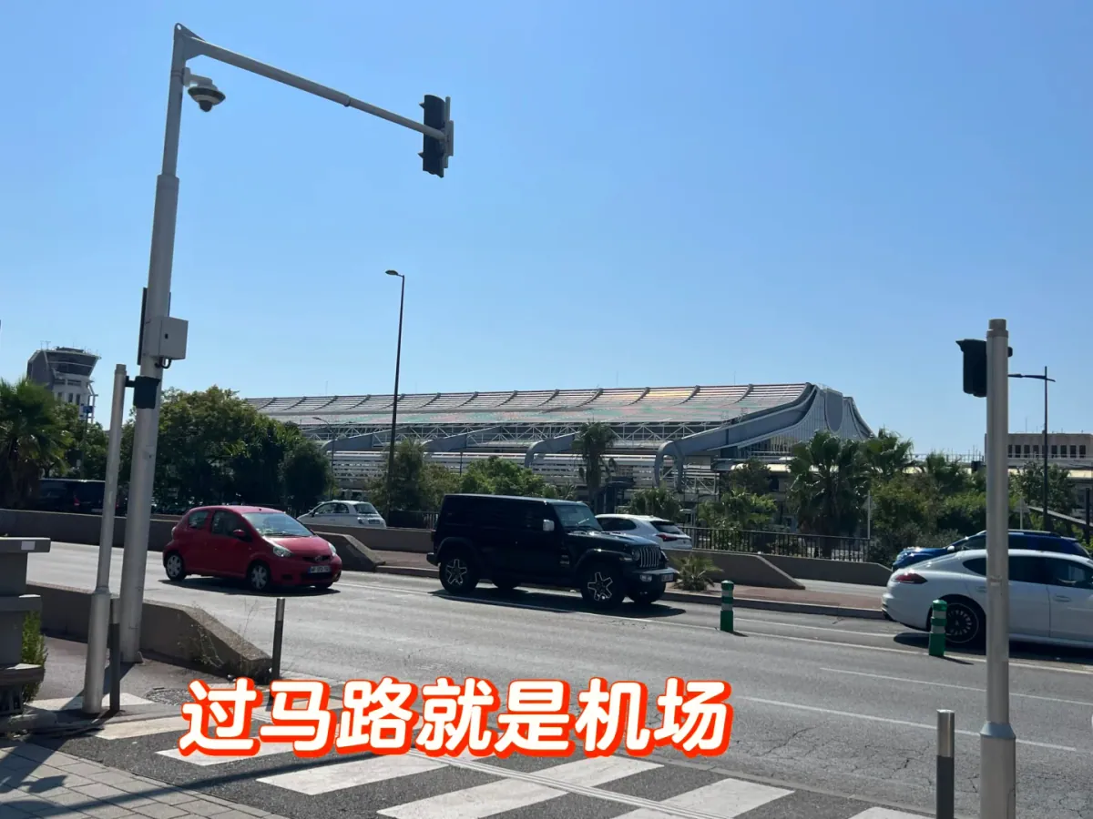 The road crossing on the way from Saint-Augustin to the airport: zebra crossing, traffic lights and traffic, with the terminal's curved roof opposite