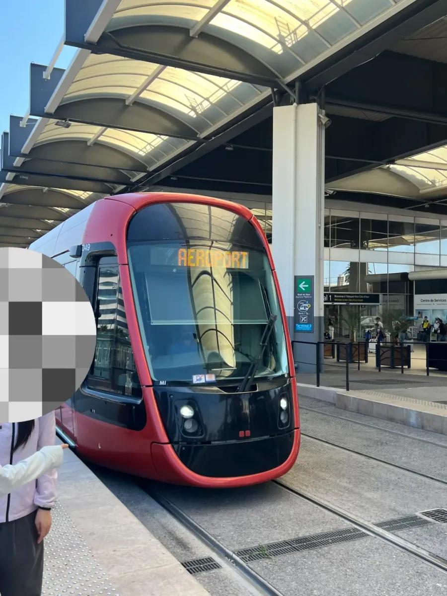 A red and white tram at the platform, its front display reading "AÉROPORT"