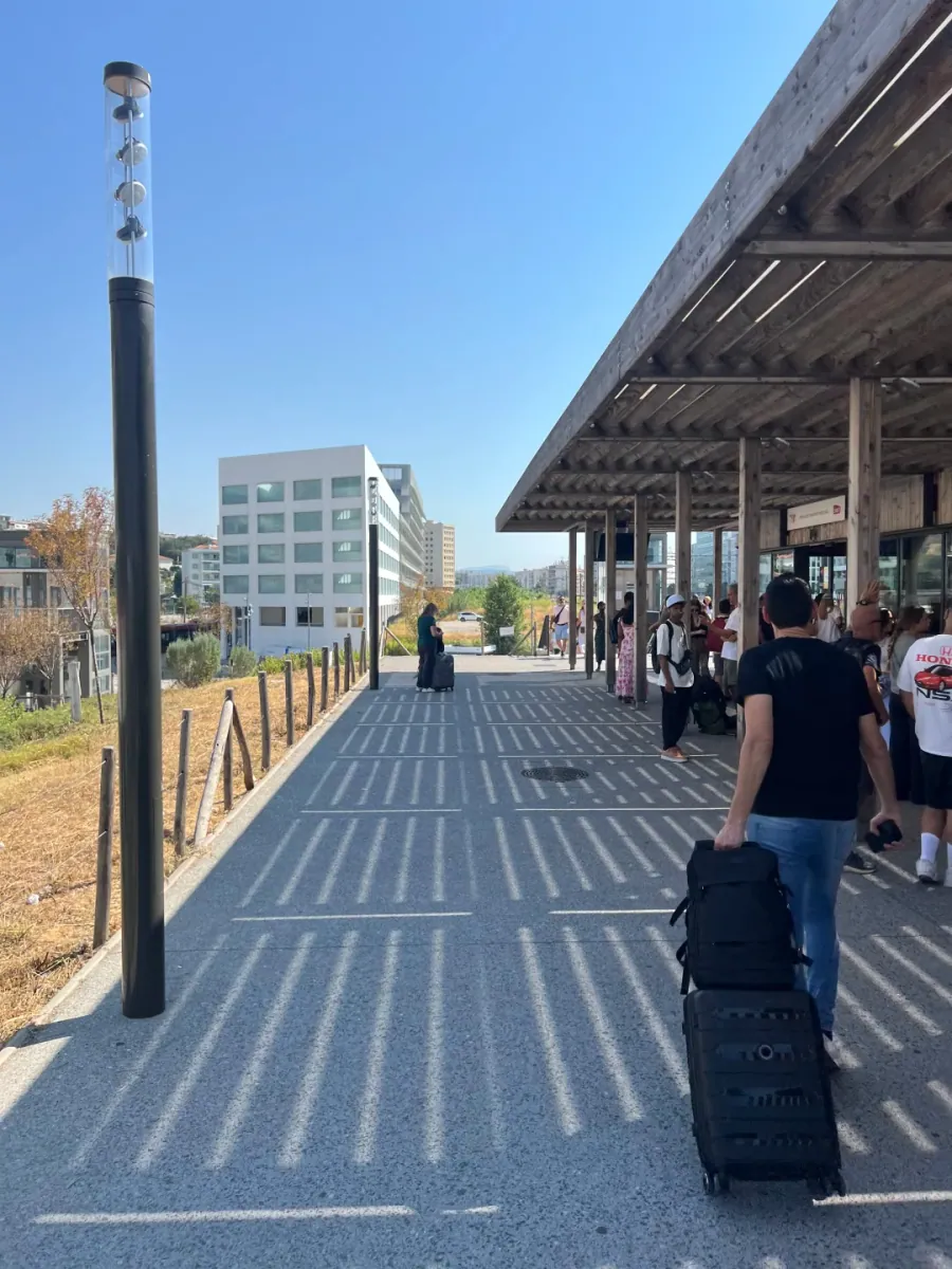 The covered walkway outside Saint-Augustin station, with travellers pulling a suitcase along the pale paving