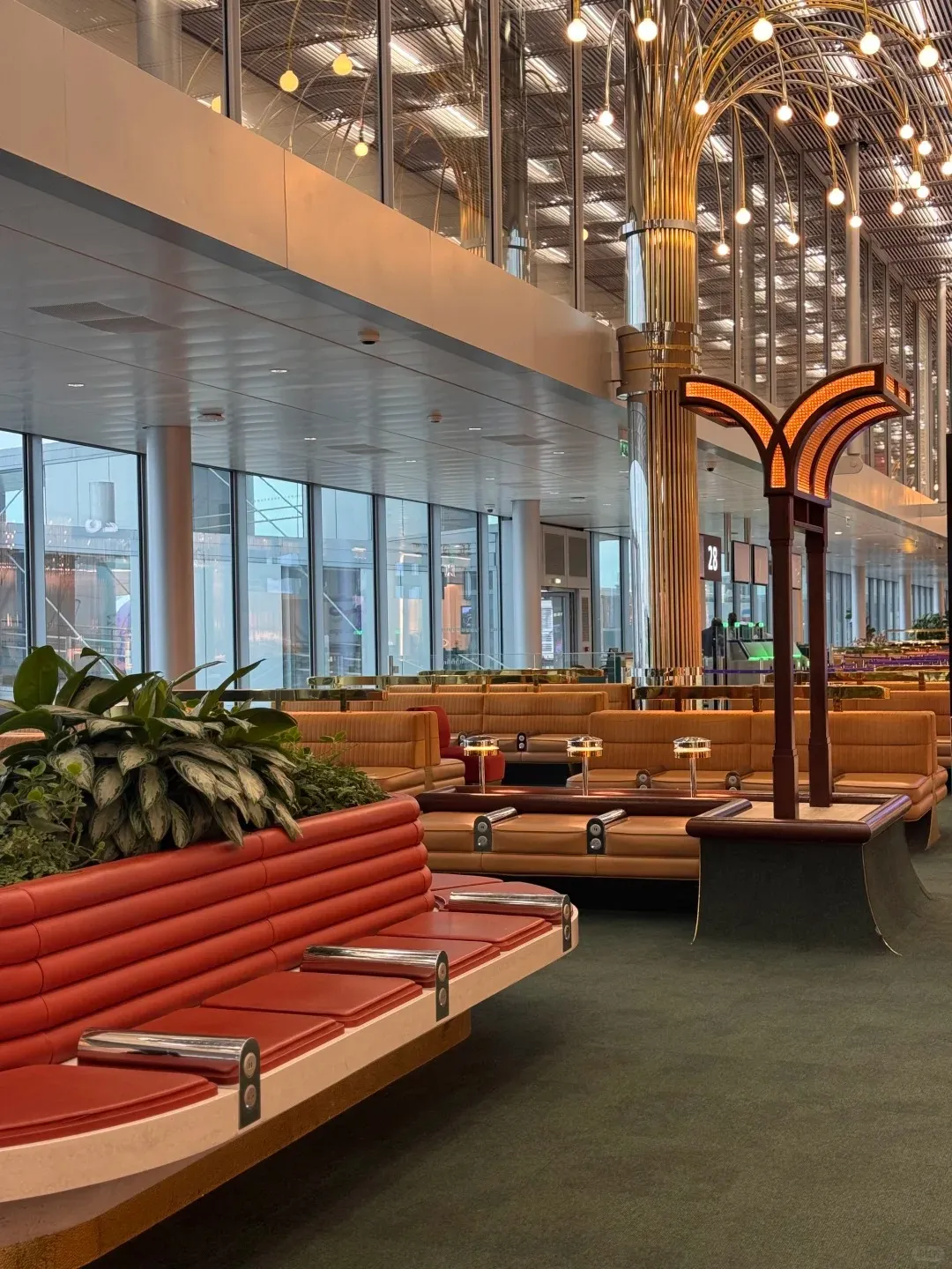 The seating area of a Paris CDG departure zone, red sofas around plants and a circular table