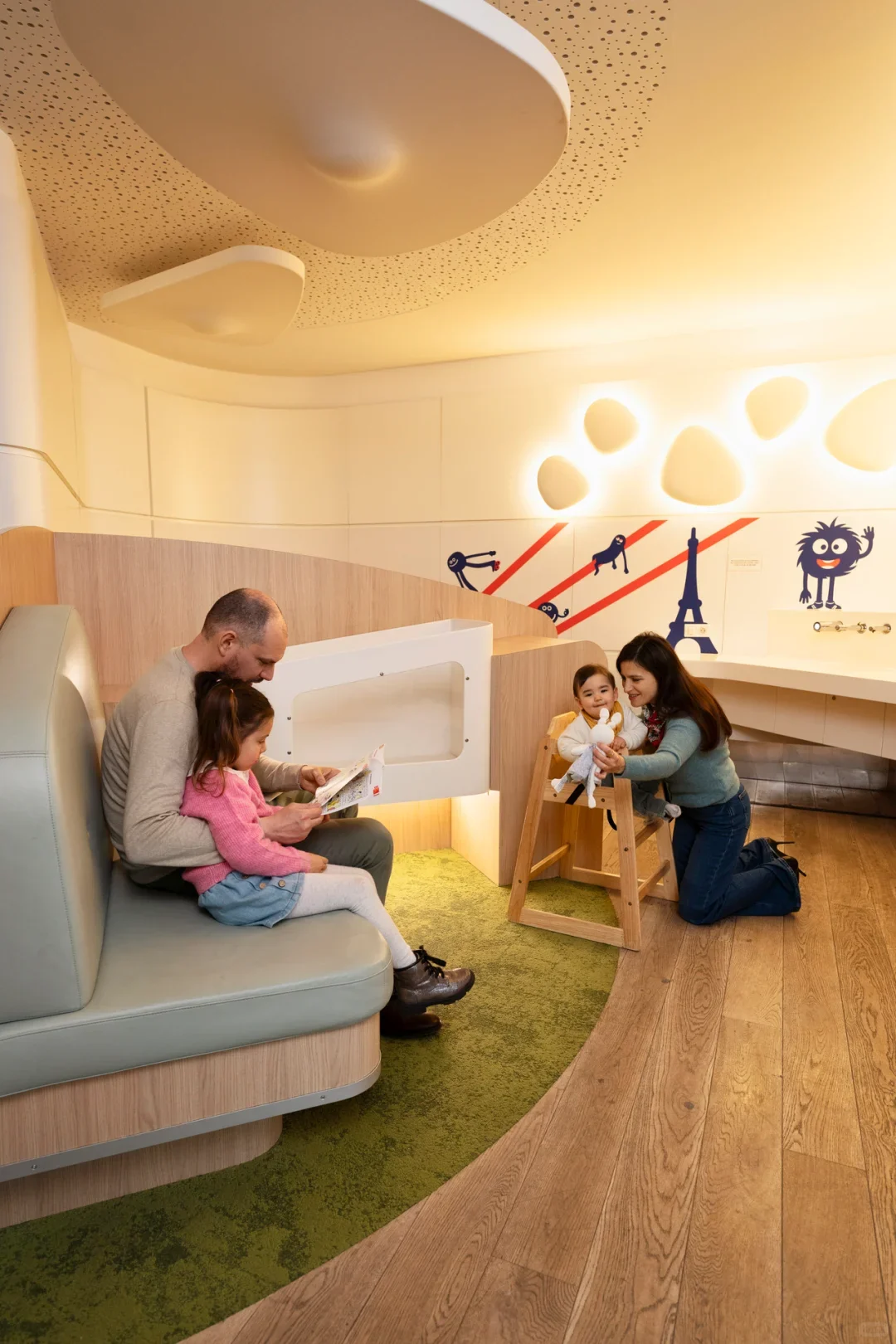 A children's play corner in a Paris CDG family area, with wooden floors, a green rug and Eiffel Tower decorations