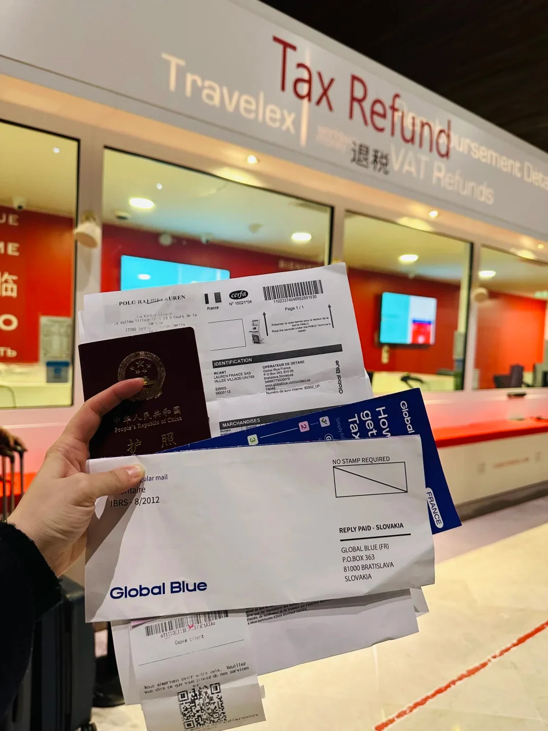 The Travelex tax-refund desk at Paris CDG, with a traveller holding a passport and Global Blue forms