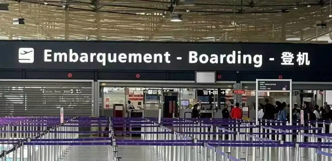 Three-language signage above a boarding gate at CDG: Embarquement / Boarding / 登机