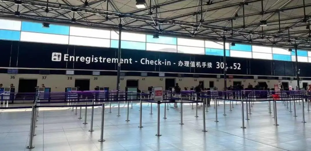 Three-language signage over the check-in area at CDG: Enregistrement / Check-in / 办理值机手续, with counters 30–52