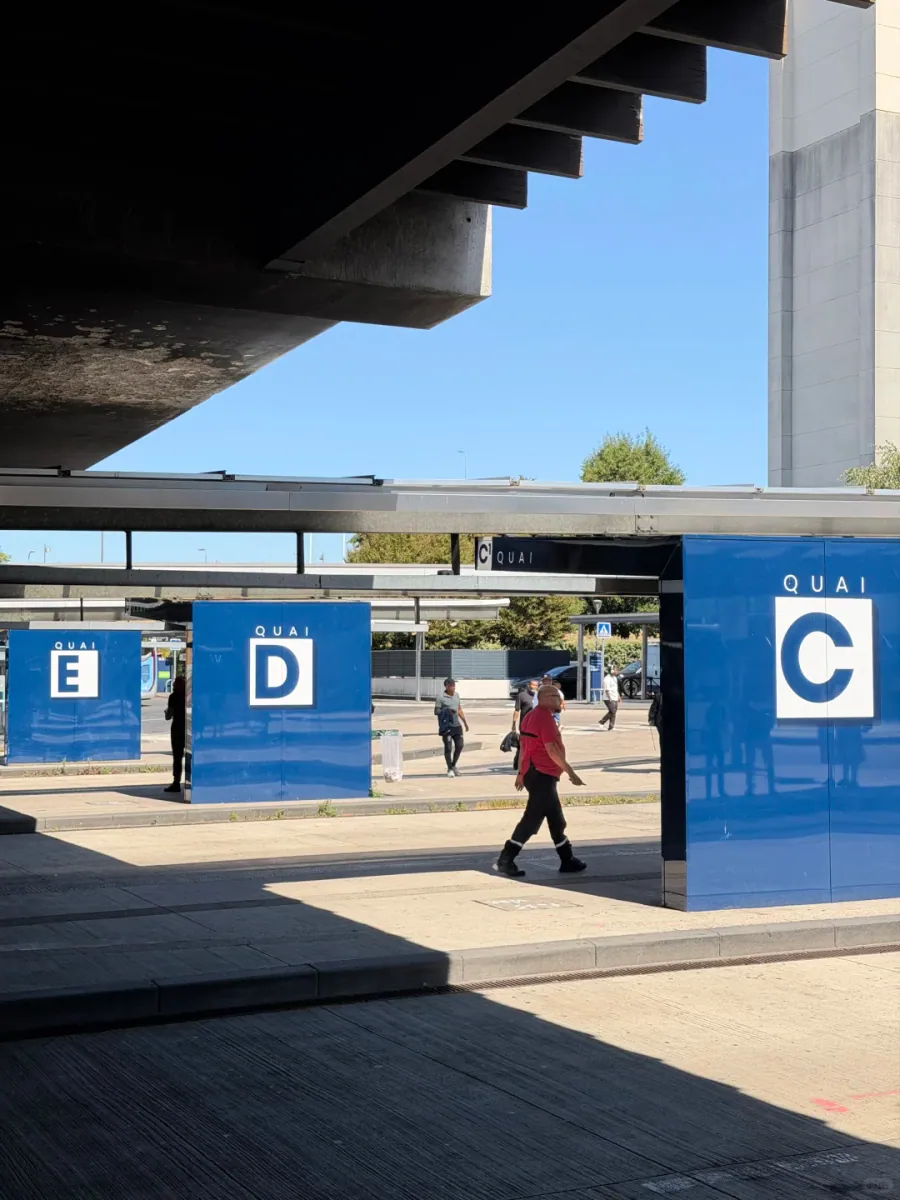 The coach bays outside the terminal: blue pillars marked QUAI C, QUAI D and QUAI E under a concrete overpass