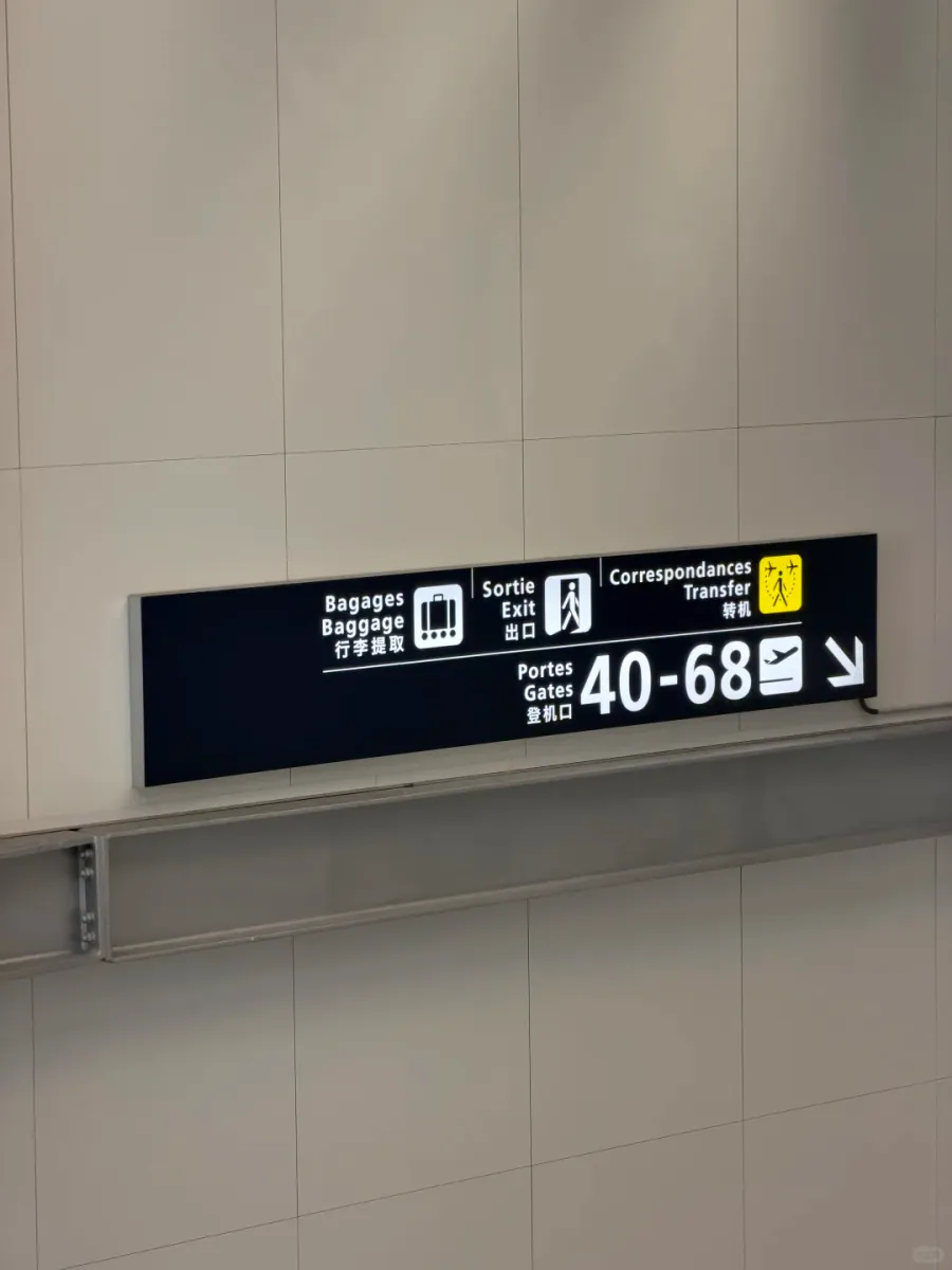 An overhead sign with Bagages / 行李提取, Sortie / 出口 and Correspondances / 转机 on the left, and "Portes / Gates 40-68 登机口" with a downward arrow on the right