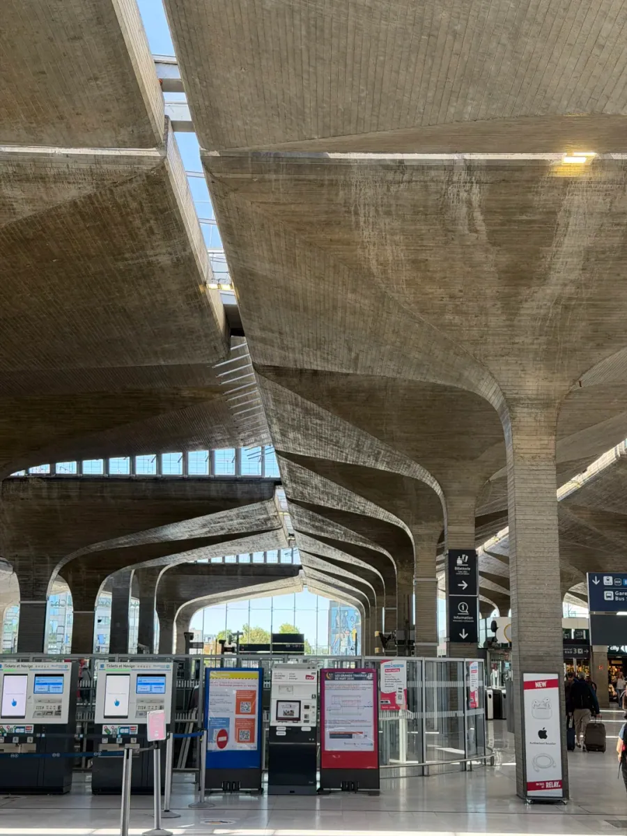 The station hall: a row of Tickets et Navigo machines and a Relay shop beneath curved concrete vaults and slanted columns