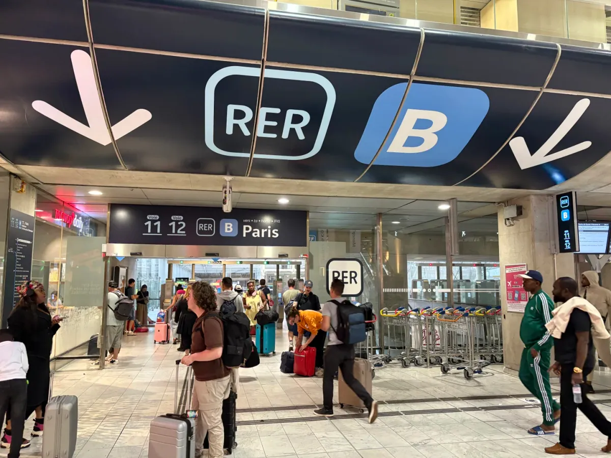The entrance to the RER B platforms: a large RER B logo and two downward arrows on a dark blue ceiling, with Voie 11, 12 and Paris on the sign below