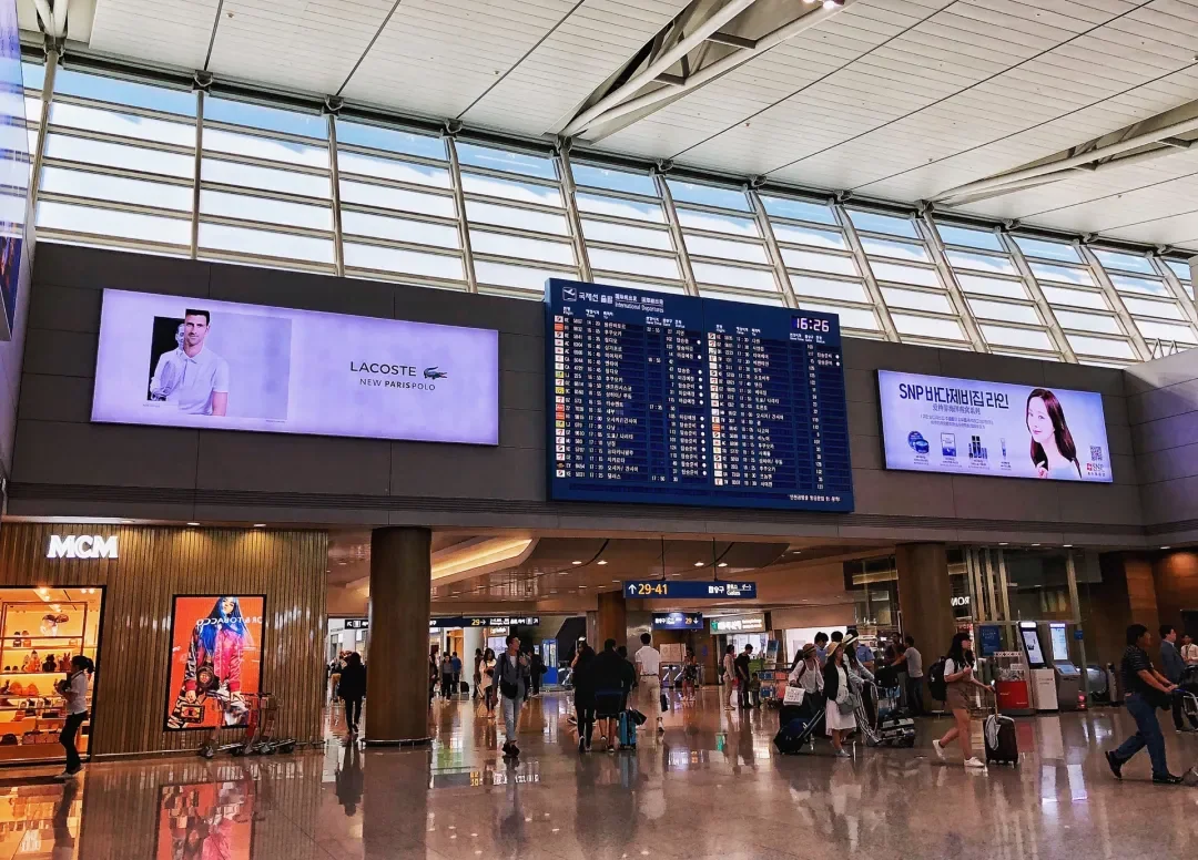 The arrivals hall at Incheon T1, with flight boards and shops