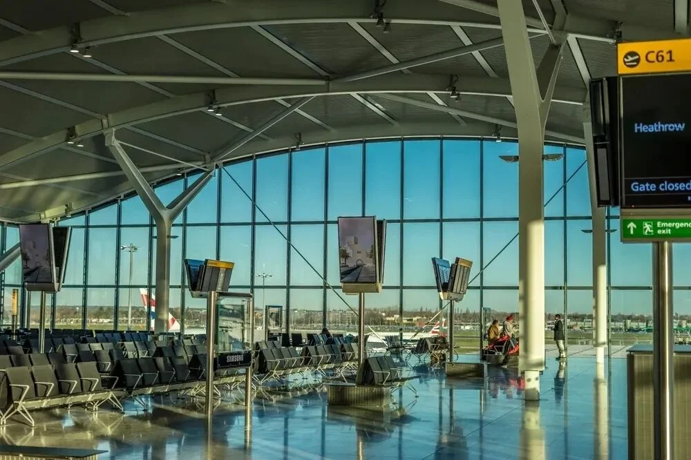 Seating at a Heathrow gate, with the apron visible through floor-to-ceiling windows