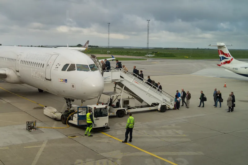 Boarding auf dem Vorfeld: Passagiere steigen die Treppe zu einem Jet von Atlantic Airways hinauf, während Bodenpersonal bereitsteht.