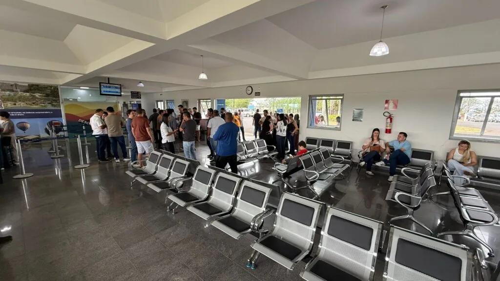 Im Terminal des Araxá Airport: eine Schlange am Check-in-Schalter und Reihen von Metallsitzen vor den Glastüren zum Vorfeld.