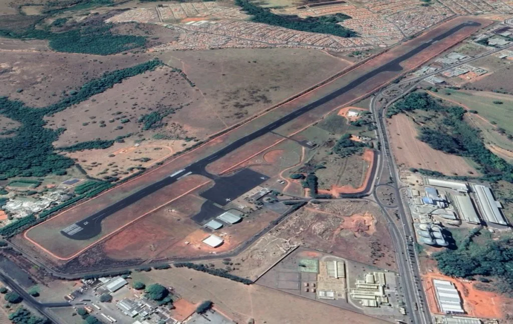 Luftaufnahme des Araxá Airport: eine einzelne Asphaltbahn in rotem Plateauland, Vorfeld und Hangars neben ihrer Mitte.