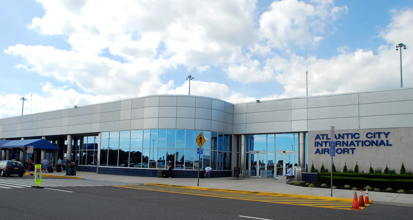 Die Landseite des Terminals — silberne Verkleidung und breite Verglasung, rechts der Schriftzug „ATLANTIC CITY INTERNATIONAL AIRPORT“.