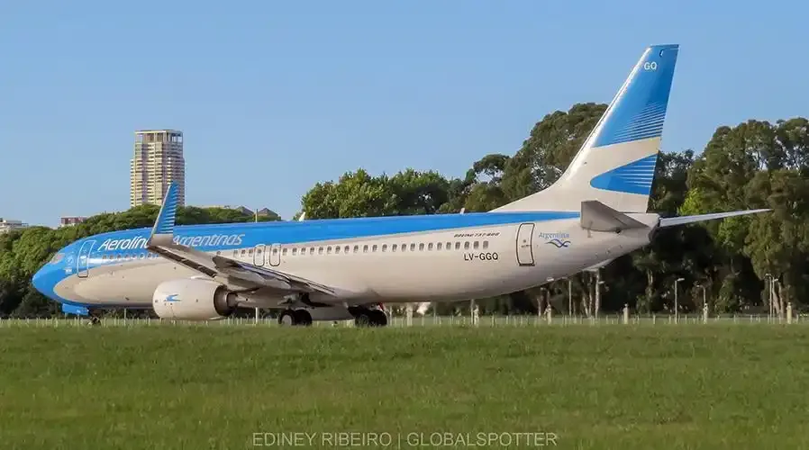 Eine Boeing 737 von Aerolíneas Argentinas, dahinter Hochhäuser und Bäume.