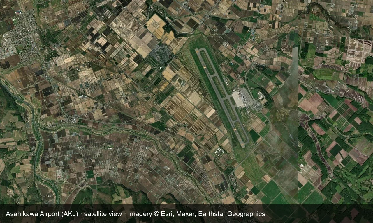 Satellitenansicht: Asahikawas Startbahn liegt zwischen Ackerland und Hügeln im Zentrum Hokkaidos, Terminal und Vorfeld daneben.