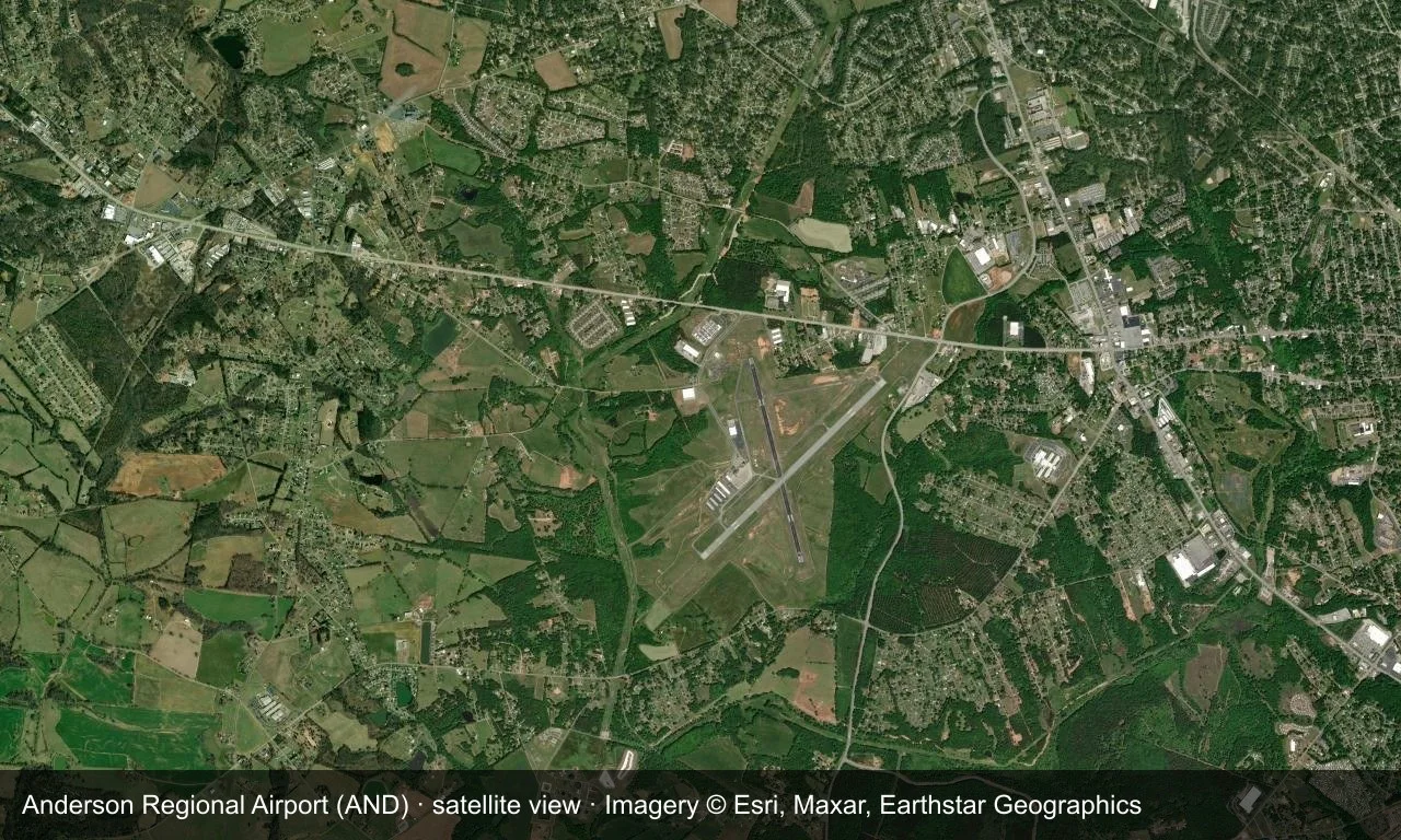 Satellitenansicht: Zwei Startbahnen kreuzen sich in grüner Landschaft, Terminal und Vorfeld liegen nahe der Kreuzung.