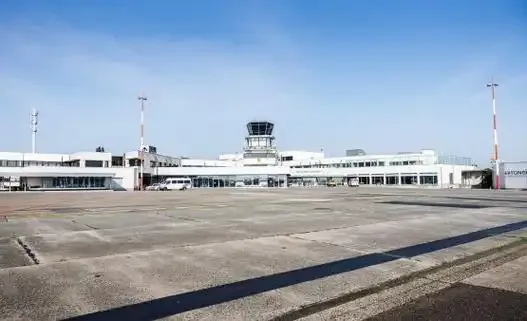 Das flache weiße Terminal, aus dessen Mitte der dunkle Kontrollturm über das Vorfeld ragt.