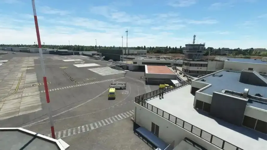 Blick vom Dach des Terminals über das Vorfeld – Turm, Abstellpositionen und Bodenfahrzeuge im Bild.