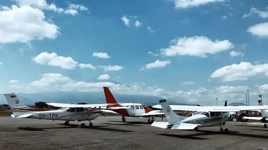Leichtflugzeuge auf dem Vorfeld — eine Reihe Cessnas unter den Wolken, am Horizont Berge.
