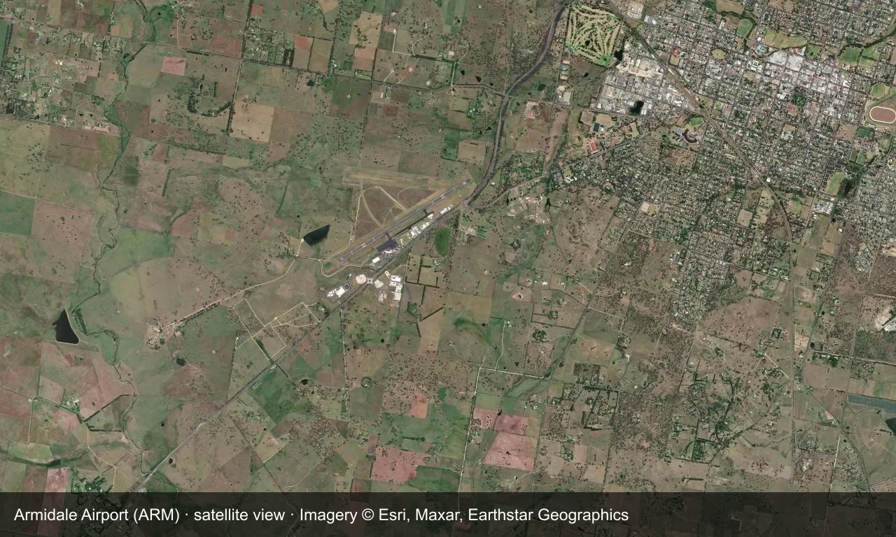 Satellitenansicht: Armidales Startbahnen liegen zwischen Hügeln und Farmland des New-England-Tablelands, mit Terminal und Vorfeld neben dem Flugfeld.