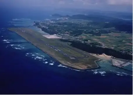 Amami aus der Luft – die Startbahn entlang der Küste, darunter das riffdurchsetzte Wasser.