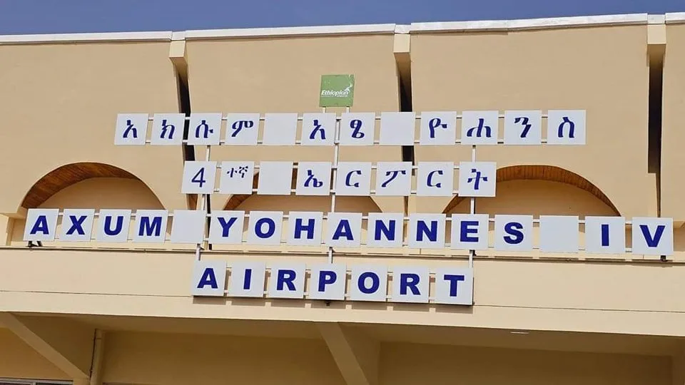Die Namenstafel am Terminal des Flughafens Axum — Amharisch neben „AXUM YOHANNES IV AIRPORT“, darüber das Zeichen von Ethiopian Airlines (aufgenommen nach der Wiedereröffnung 2024).