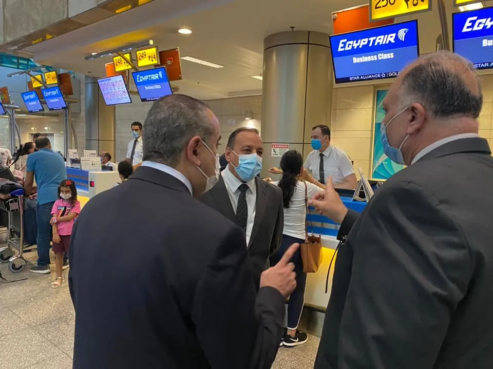 EgyptAirs Business-Class-Check-in-Bereich – blaue Schalter unter den Fluginformationsanzeigen, während Passagiere einchecken (Ägyptisches Ministerium für Zivilluftfahrt, August 2021, über den State Information Service).