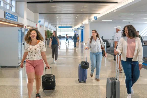 Der Ankunftskorridor – Reisende mit Gepäck gehen unter dem Schild „Arrivals“ zum Ausgang.