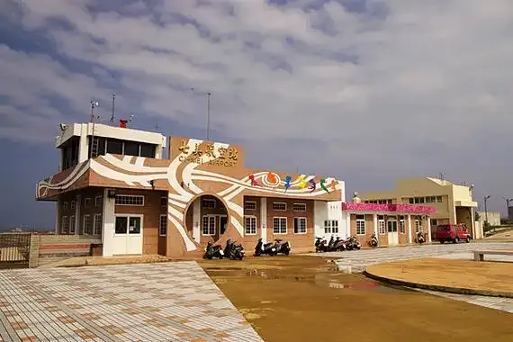 Qimei Airport's small terminal, with a wavy painted facade and scooters parked in front.