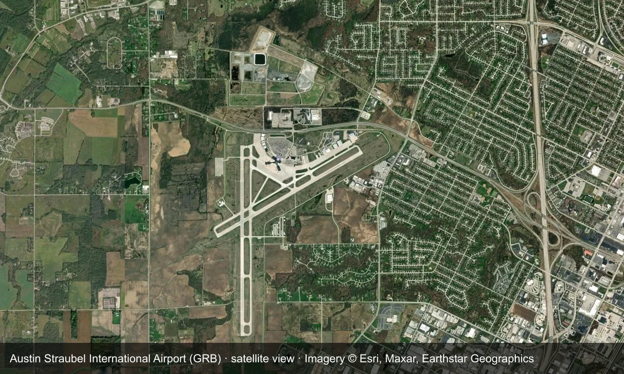 Satellitenansicht: Die beiden Startbahnen von Green Bay liegen in der Ebene am Michigansee, Terminal und Vorfeld am Flugfeld.