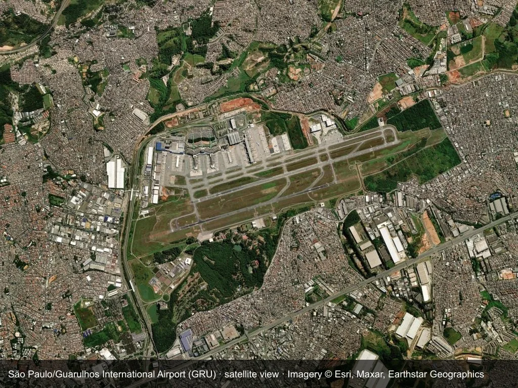 Satellitenansicht: Der Flughafen São Paulo Guarulhos (GRU) liegt eingebettet in Stadt, Küste oder Gelände, die Startbahn durchquert das Bild.