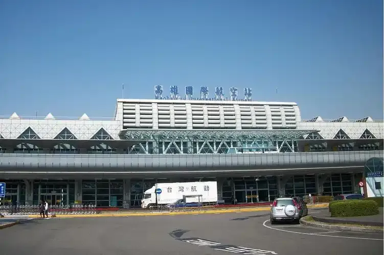 The front of Kaohsiung International Airport's terminal, with glass curtain walls beneath its triangular roof.