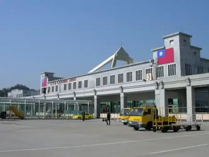 Kinmen Airport's terminal exterior, with the ROC flag painted on the wall and yellow service vehicles parked outside.