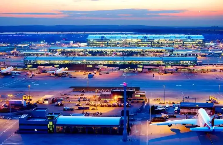 Heathrow in der Dämmerung – die beleuchteten Terminals, ein Flugzeug von Etihad auf dem Vorfeld.