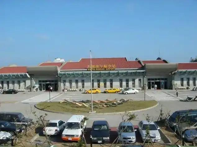 The front of Matsu Nangan Airport's terminal with its red-tiled roof, looking across the car park and roundabout.