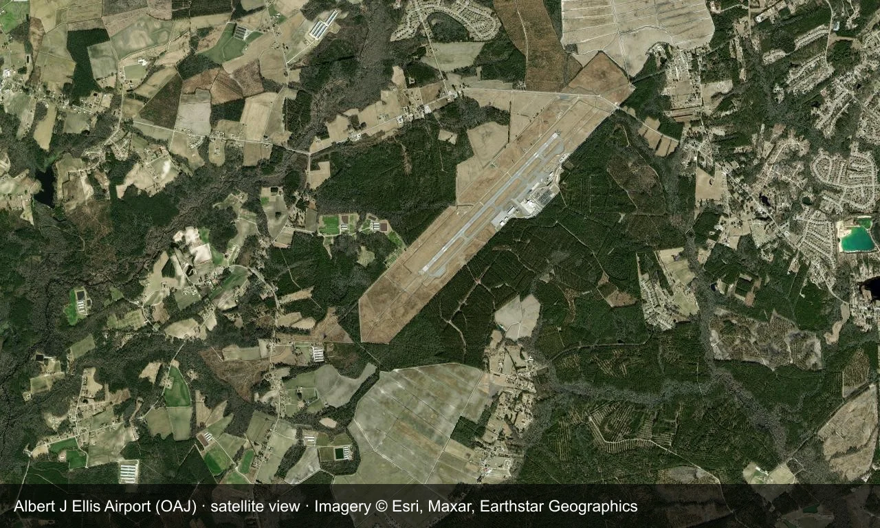 Satellitenansicht: Die Startbahn von Jacksonville liegt zwischen Wald und Ackerland in der Küstenebene von North Carolina, Terminal und Vorfeld daneben.